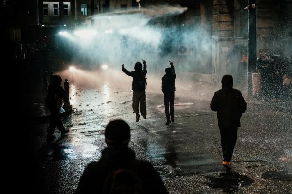 Protesters jump in front of the water cannon.