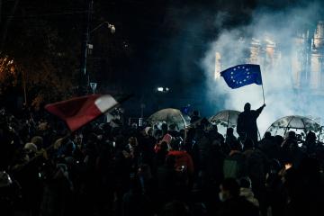 A man holds a European Union flag behind the barricades. To defend themselves from water cannons, pe ...
